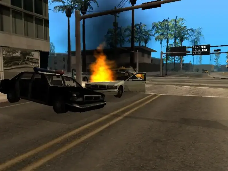 Vehículos de emergencia en un accidente de tráfico con fuego en la calle, escena de videojuego de estilo old school con palm trees y señalización de tránsito.