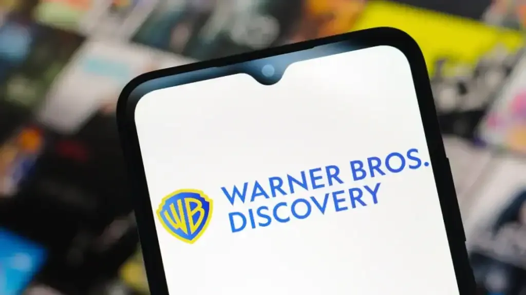 Logo de Warner Bros. Discovery mostrado en la pantalla de un teléfono, relacionado con la noticia de su posible venta por más de 50 mil millones de dólares.